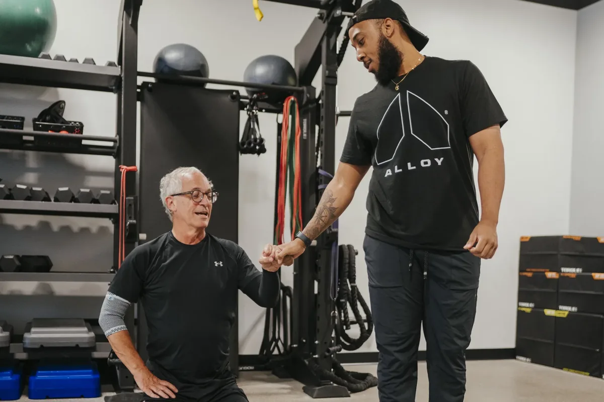 A coach fist-bumps a seated member during a calm check-in between sets
