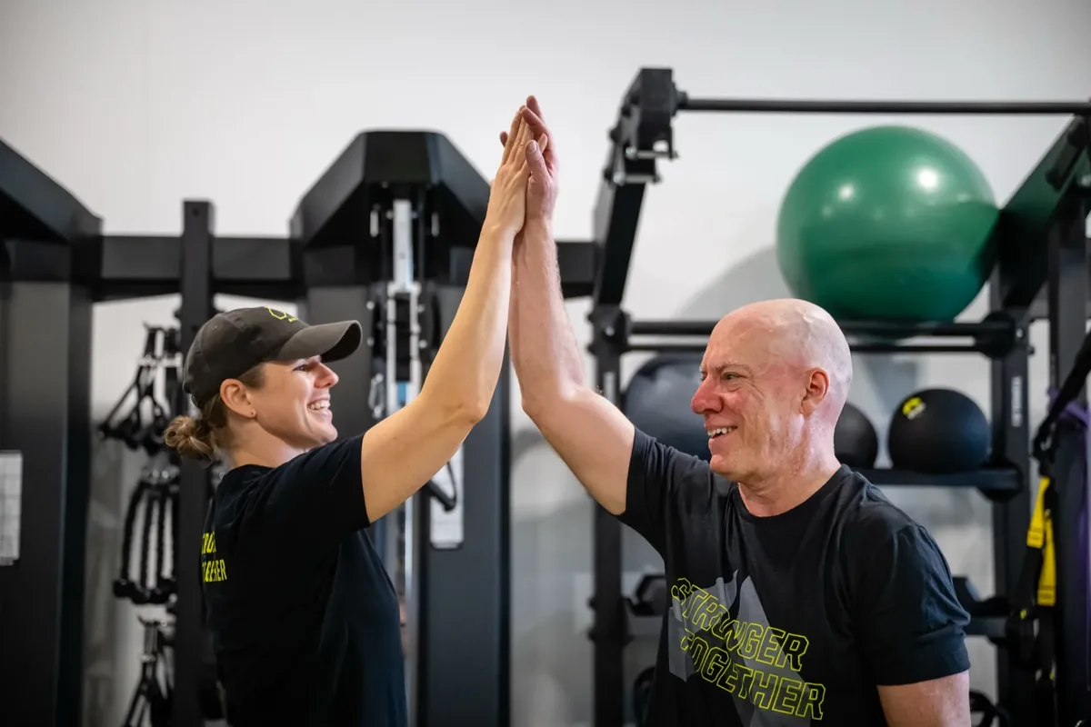 Alloy Madison East coach and member sharing a high-five after a strength training session