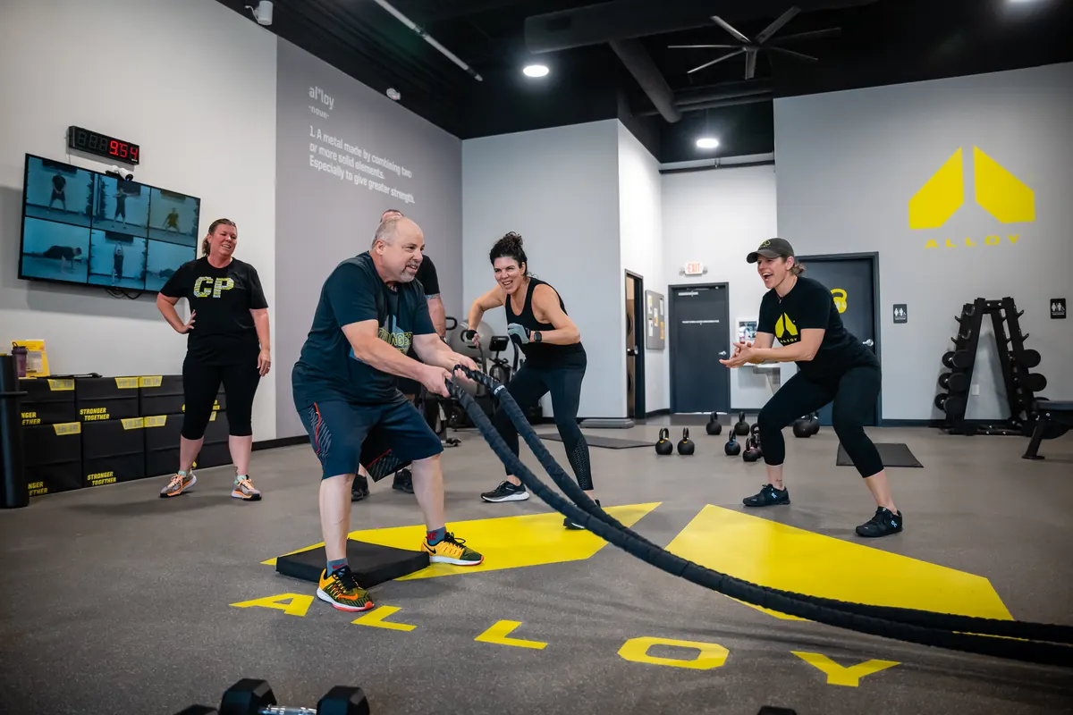 Alloy members working out together with battle ropes in a coached small group